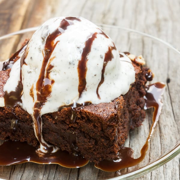 A Sabor Ice Cream brownie topped with a scoop of vanilla ice cream and chocolate syrup.