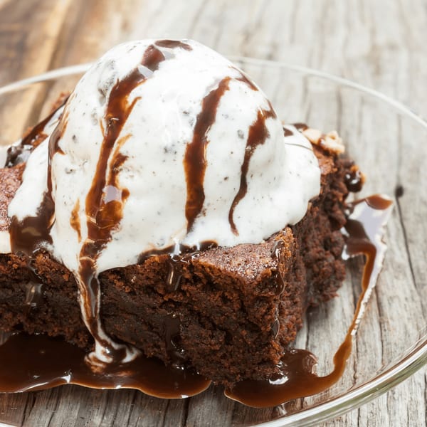 A Sabor Ice Cream brownie topped with a scoop of vanilla ice cream and chocolate syrup.